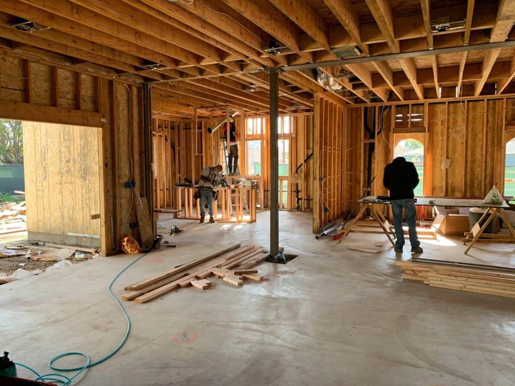 Arbeiter errichten das Gerüst eines Hauses und demonstrieren dabei die Innenausbauarbeiten und den Bauprozess.